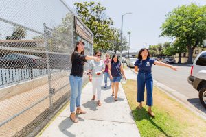 Four people standing on the sidewalk next to a park